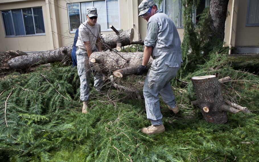Airman 1st Class Matthew Chance (left) and Staff Sgt. Stephen Coakley with the 374th Civil Engineer Squadron help in the effort to clear out debris at Yokota Air Base Thursday left from Typhoon Roke.
