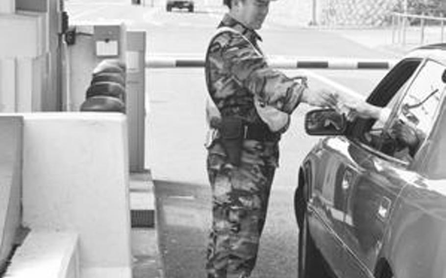A South Korean gate guard checks identification of a driver in 2008 at the then newly-named Commissary Gate on Yongsan Garrison, South Korea. Garrison officials then gave all the numbered gates common sense names, mirroring what community members usually call the gates.