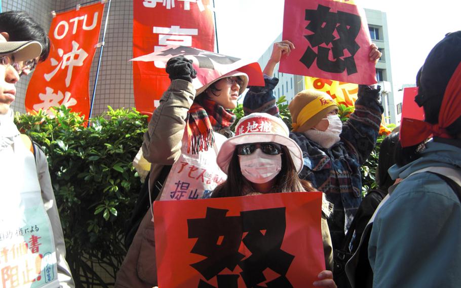 Protesters wave red cards that read 'wrath' in Chinese after discovering that an environmental assessment report for a new Marine Corps runway planned to be built on Camp Schwab had been delivered to the Okinawa prefectural government office on Dec. 28, 2011, before office hours.