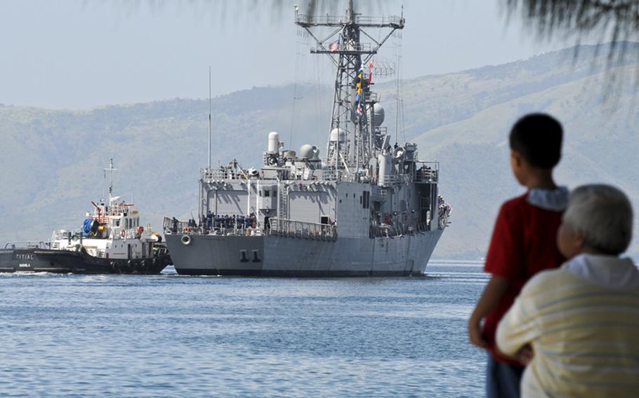 A Filipino father and son watch the guided-missile frigate USS Crommelin get under way after participating in Cooperation Afloat Readiness and Training Philippines (CARAT) exercise in October, 2010.