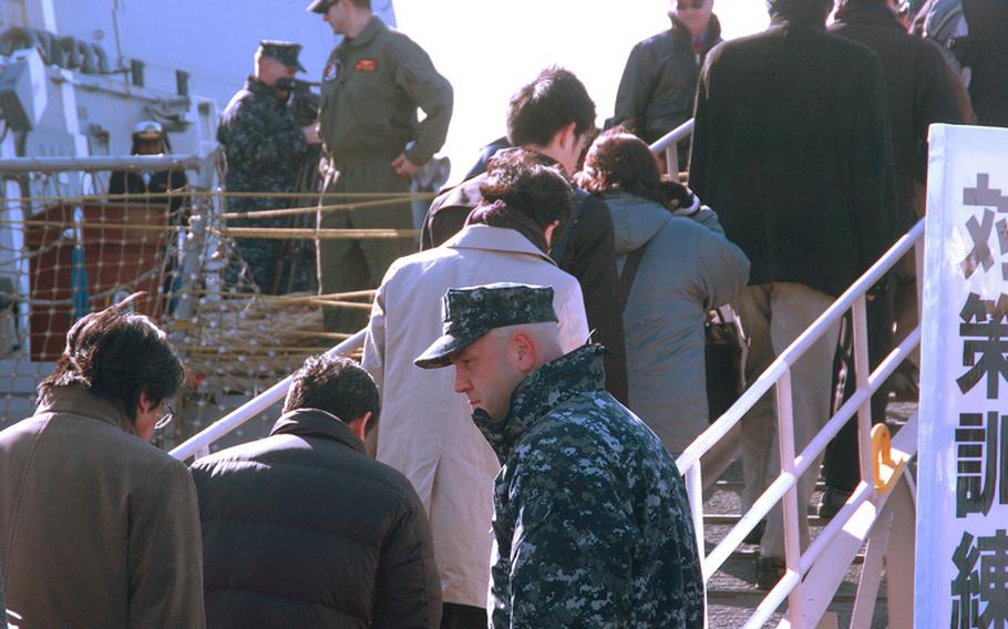 A USS Lassen sailor bows to each civilian during a disaster evacuation exercise at the Tokyo Lumber Pier on Feb. 3, 2012. The Lassen and the Army's USS Fort McHenry each helped evacuate dozens of people playing the roles of stranded commuters. About 10,000 people citywide took part in the drill, which was designed to improve upon the city's performance after millions of commuters were left stranded following the March 11, 2011 earthquake and tsunami.
