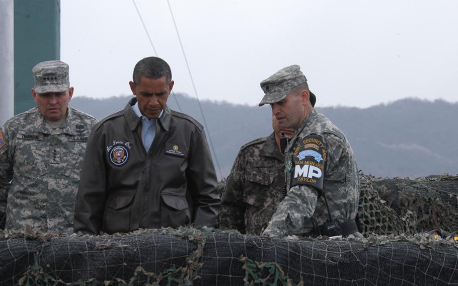 President Barack Obama looks at a map as he is briefed March 25, 2012, during a visit to Korea's Demilitarized Zone. Lt. Col. Ed Taylor, commander of the United Nations Command Security Battalion - Joint Security Area, right, describes some DMZ landmarks on the map. U.S. Forces Korea commander Gen. James Thurman, left, looks on.