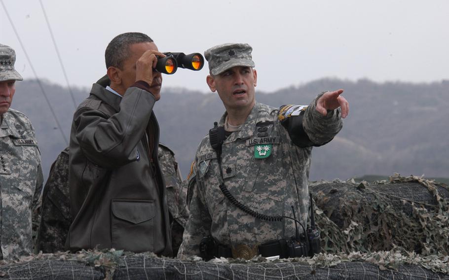 President Barack Obama looks through binoculars into North Korea on March 25, 2012, from Observation Point Ouellette in the Demilitarized Zone. Lt. Col. Ed Taylor, commander of the United Nations Command Security Battalion - Joint Security Area, right, describes some of the landmarks at which the president was looking.