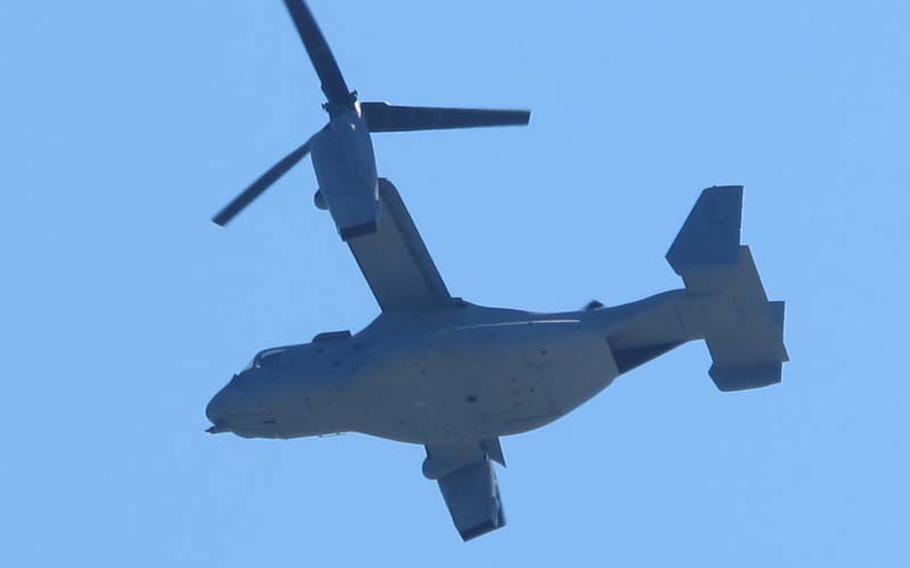 The second MV-22 Osprey to leave the ground in Japan flies over the protesters and news outlets at the end of the runway.