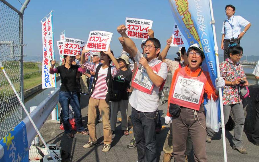 Protesters shout slogans at the MV-22 Osprey as flight operations commece Friday in Iwakuni, Japan.
