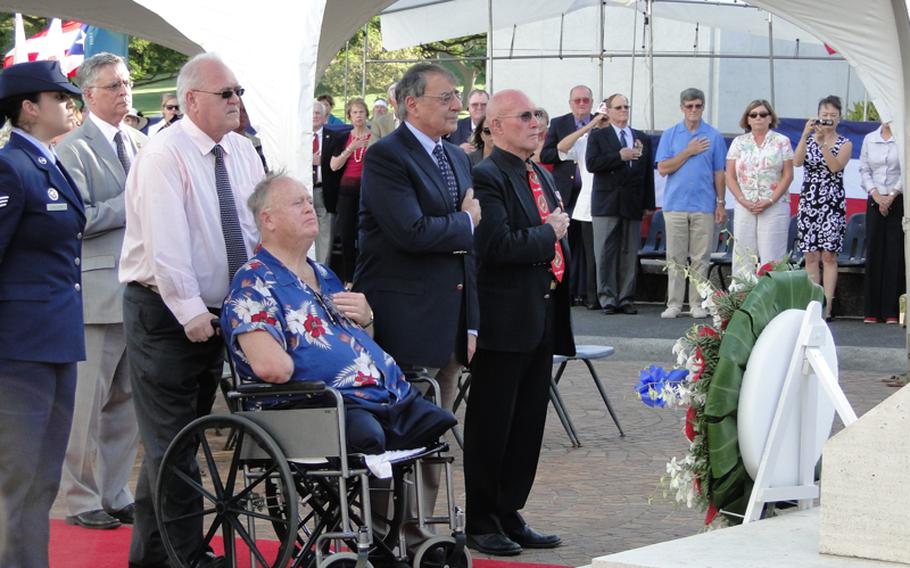 Former Sen. Max Cleland, a Vietnam veteran, in wheelchair, and Defense Secretary Leon Panetta, to his left, join others in observing the nation's veterans during a Veterans Day ceremony Nov. 11, 2012, at the National Memorial Cemetery of the Pacific in Hawaii. The crowd is facing a wreath Panetta laid in honor of Veterans Day.
