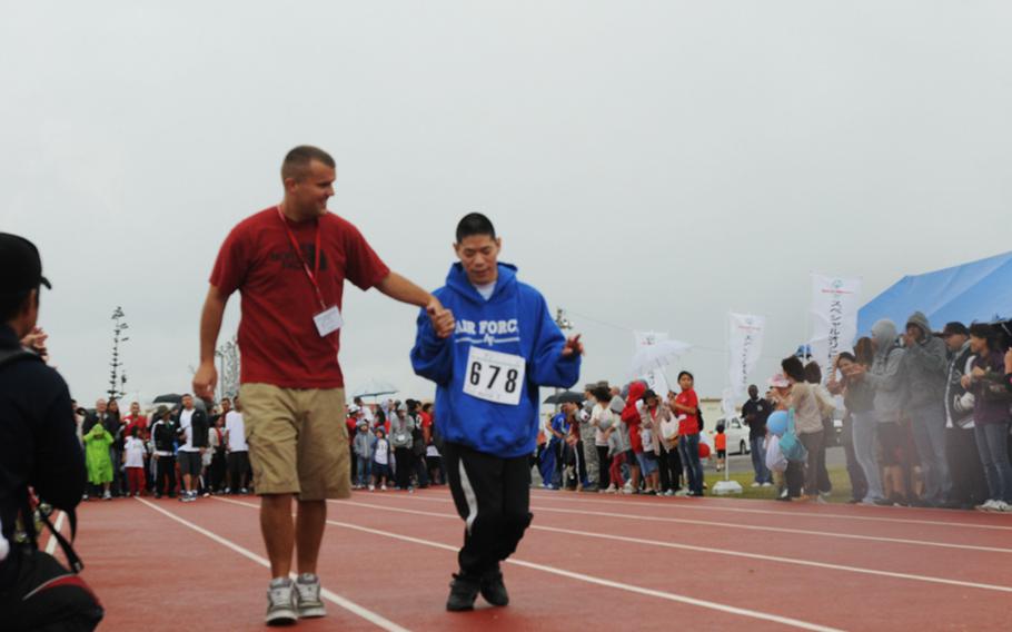 Marine Sgt. Eric Thurau from Marine Corps Air Station Futenma assists Kota Yane of Okinawa City in the 30-meter Dash during the 13th Kadena Special Olympics Saturday.
The inter-community event began in 2000 with about 400 athletes. Twelve years later, participants grew more than double. On Saturday’s event, about 3,000 servicemembers, civilians, their families and Japanese volunteers gather the air base to support the goodwill event.