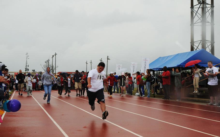 Tai Toguchi from Haebaru Town outruns his volunteer escort, Airman 1st Class Audrey McCleskey, in the 30-meter Dash during the 13th Kadena Special Olympics held at Kadena Air Base.