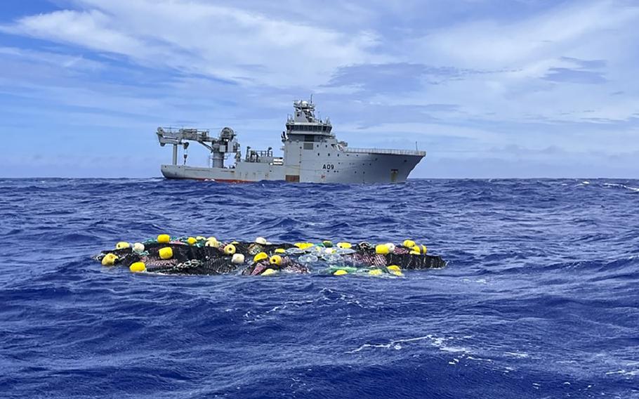 In this undated photo supplied by the New Zealand police, a shipment of cocaine floats on the surface of the Pacific Ocean with Royal New Zealand Navy vessel HMNZS Manawanui behind. New Zealand police said Wednesday, Feb. 8, 2023 they found more than 3 tons of cocaine floating in a remote part of the Pacific Ocean after it was dropped there by an international drug-smuggling syndicate.