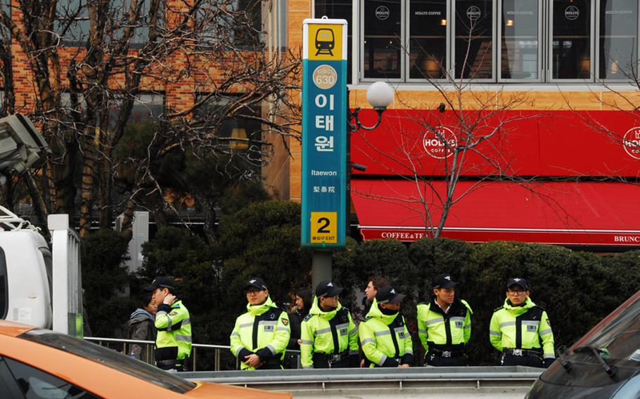 South Korean police wait for a bus in front of an Itaewon subway station exit and the Hamilton Hotel on March 6, 2013, in the area where at least one U.S. soldier allegedly shot a BB gun from a car, triggering a police chase that culminated with another soldier being shot by a South Korean police officer. 