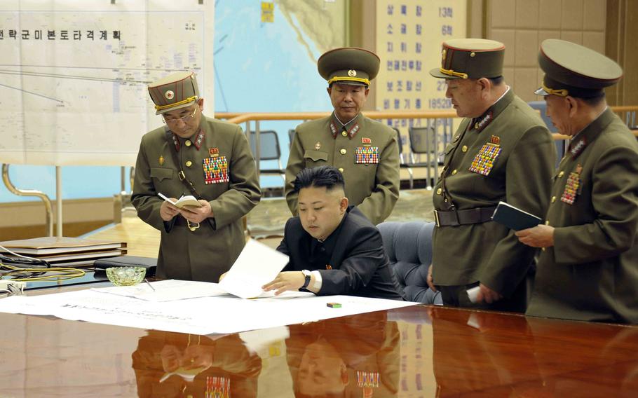 A photo provided by the state-run Korean Central News Agency (KCNA) shows North Korean leader Kim Jong Un, center, on March 29, 2013, signing an order putting rockets on standby after an urgent meeting with top generals.