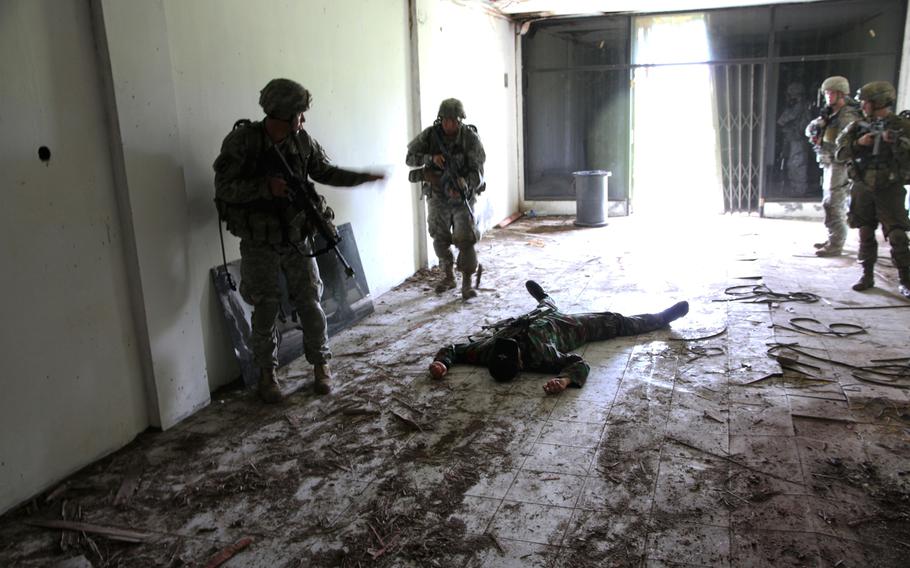 Soldiers examine a "dead" enemy as they clear a building during a mock UN peacekeeping scenario as part of Garuda Shield in Indonesia.