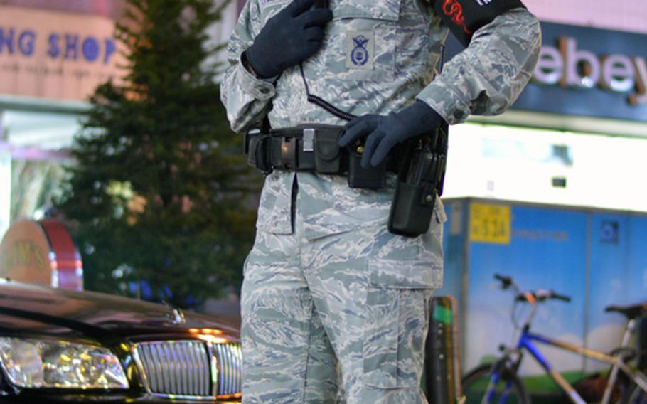 A member of the Osan Air Base joint town patrol observes U.S. servicemembers and local nations at the Shinjang Shopping Mall, the entertainment district just outside the front gate of Osan Air Base in South Korea, on March 16, 2013.