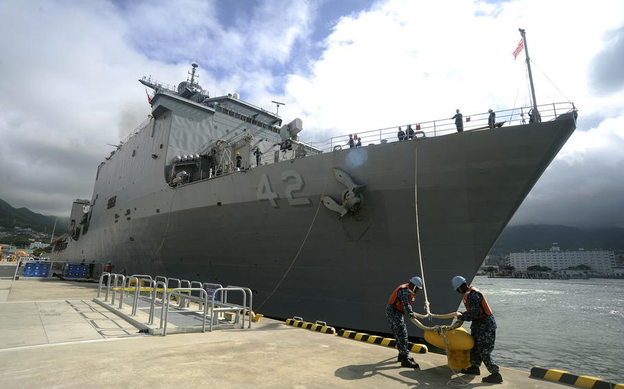 Sailors release a mooring line as the amphibious dock landing ship USS Germantown departs Sasebo, Japan, for a patrol in June 2011.