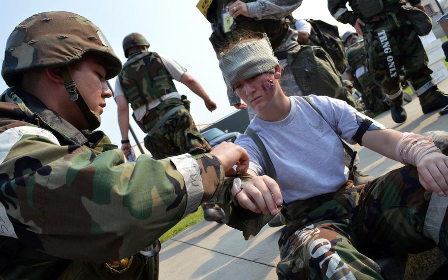 Air Force Staff Sgt. Curtis Hoofman, left, applies first aid to simulated mass casualty victim Airman 1st Class Hallie Zdanczewski outside the Osan Air Base passenger terminal during the Beverly Midnight 2013 exercise, Aug. 8, 2013.