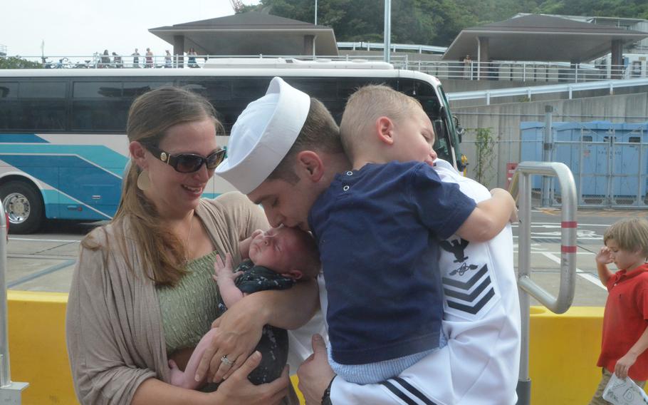 Petty Officer 1st Class Robert Dyer kisses his 4-week-old son, Reed, for the first time at Yokosuka Naval Base on Friday. About 5,000 sailors disembarked from the aircraft carrier USS George Washington, which returned to Yokosuka for a break in its ongoing Western Pacific patrol.
