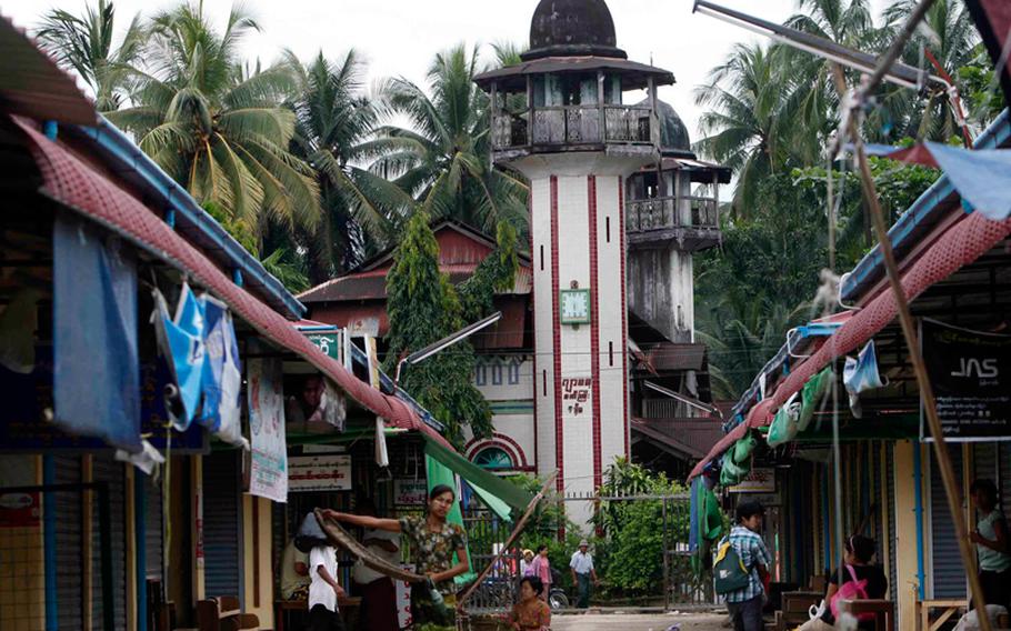 Residents walk through a quiet local bazaar near a mosque Wednesday, Oct. 2, 2013, in Thandwe, Rakhine State, western Myanmar. Terrified Muslim families hid in forests in western Myanmar on Wednesday, one day after rampaging Buddhist mobs killed a 94-year-old woman and burned dozens of homes despite the first trip to the volatile region by President Thein Sein since unrest erupted last year.