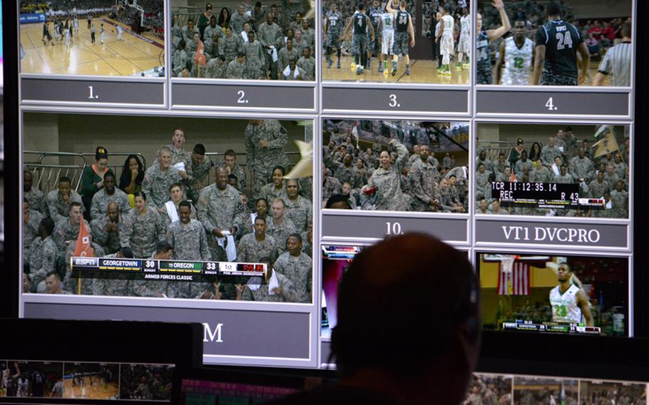 An ESPN production crewmember watchs a large monitor during the NCAA season-opening 2013 Armed Forces Classic at Camp Humphreys, South Korea, on Saturday, Nov. 9, 2013.