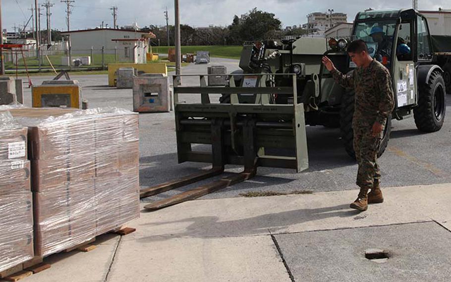 Pfc. Arturo Menchaca uses hand signals to direct Lance Cpl. Bryce E. Sanglay as he drives an extended boom forklift at Marine Corps Air Station Futenma, Okinawa, Japan, Sunday, Nov. 10, 2013, during preparation for a humanitarian assistance and disaster relief mission to the Philippines after Typhoon Haiyan.