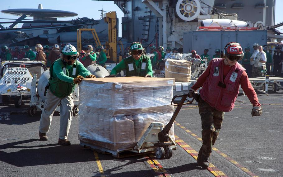 Sailors aboard the USS George Washington move a pallet of drinking water across the aircraft carrier's flight deck, as the George Washington Strike Group supports the 3rd Marine Expeditionary Brigade's relief efforts in the Philippines devastated by Super Typhoon Haiyan.