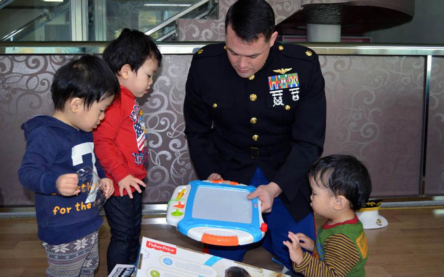 U.S. Marine Maj. Bryon deCastro unwrap a toy for orphans at Jacob's House orphanage, Pyeongtaek, South Korea, Dec. 22, 2013. DeCastro led the Toys for Tots donation drive held at Osan Air Base. 