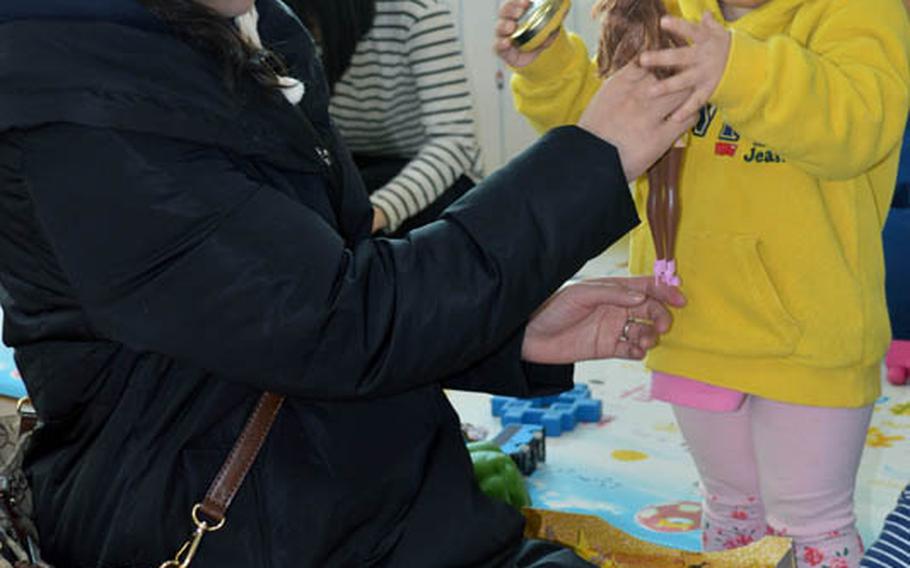 Christina JuYong Park helps presents a toy for orphan at Jacob's House orphanage, Pyeongtaek, South Korea, Dec. 22, 2013. Park is the spouse of U.S. Marine Maj. Bryon deCastro. 