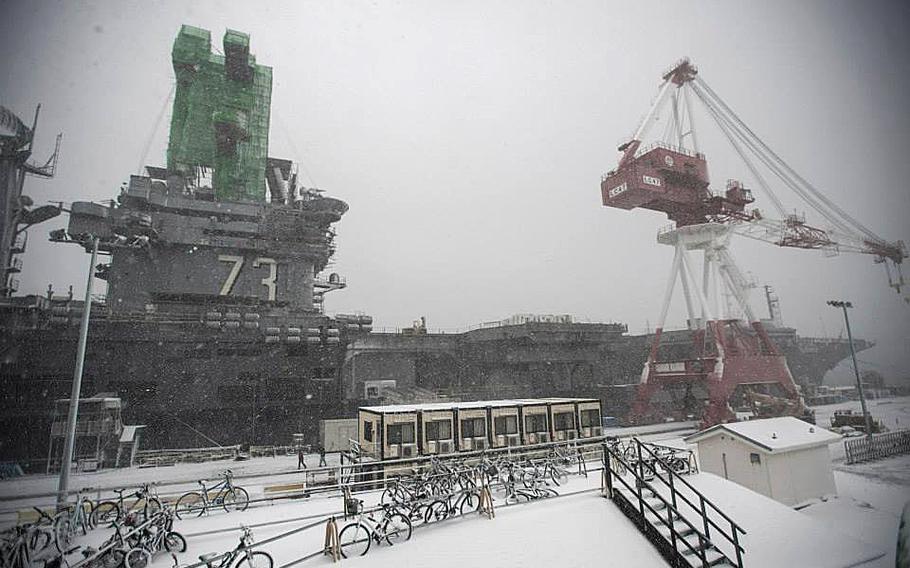 The aircraft carrier USS George Washington is moored at Yokosuka Naval Base amid a snowstorm expected to bring more than one foot of snow to other U.S. military bases in the western part of the Tokyo region, along with gale force winds.