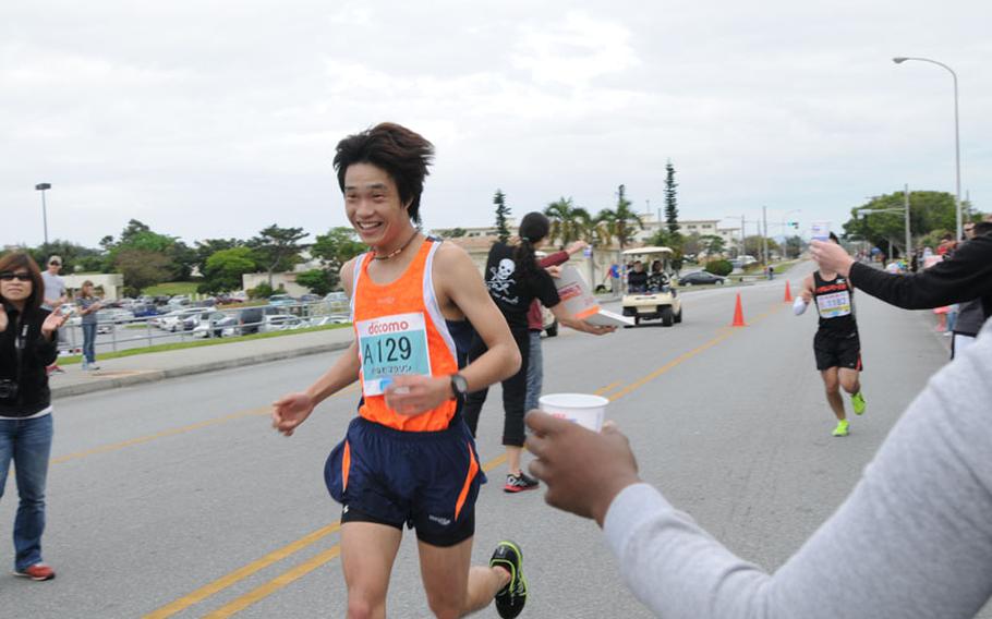 Volunteers offer water and snacks for runners during the 22nd Annual Okinawa Marathon at Kadena Air Base, Okinawa, Feb. 16, 2014. 