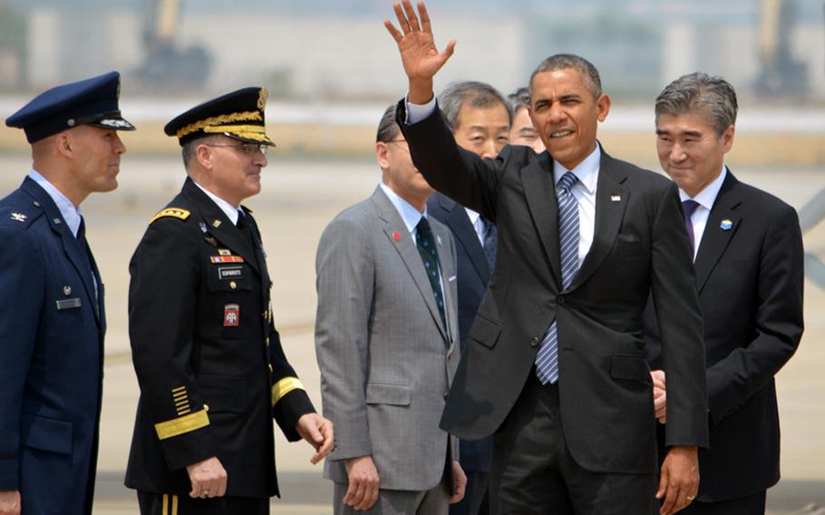 President Barack Obama waves to the international media after stepping off Air Force One at Osan Air Base, South Korea, on Friday, April 25, 2014. Obama was scheduled to meet South Korean President Geun-hye Park later in the day.