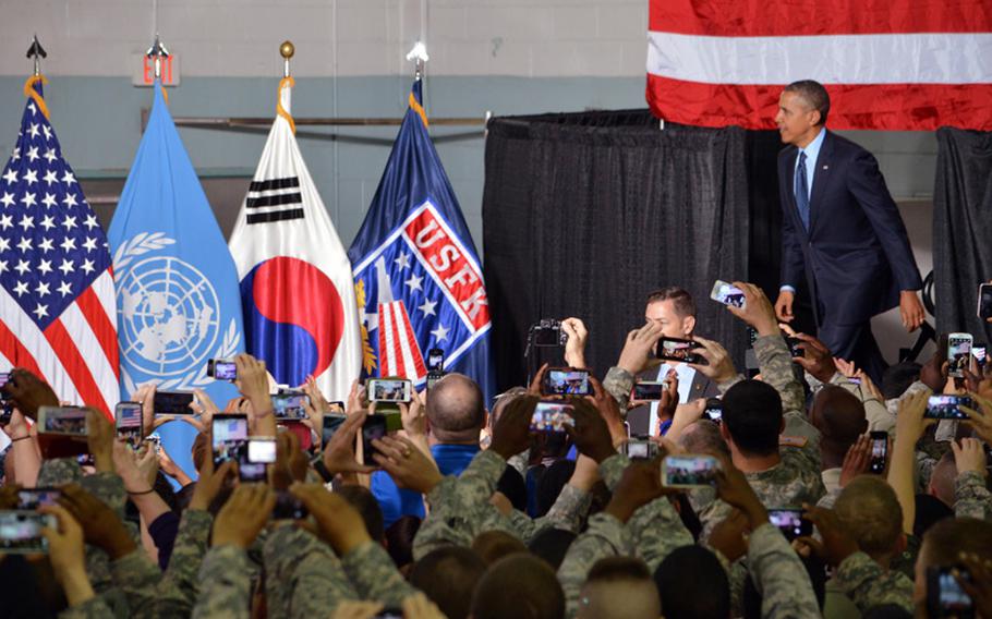 President Barack Obama walks on stage as servicemembers and families take photos at Yongsan Garrison, South Korea, on Saturday, April 26, 2014. The president gave a speech to the troops prior to departing South Korea for Malaysia.