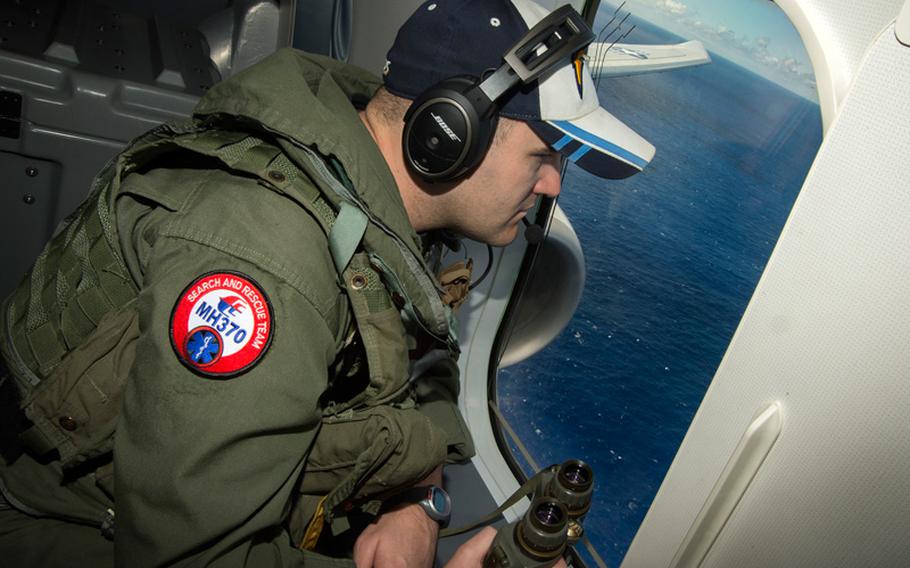 Naval Aircrewman (Operator) 2nd Class Karl Shinn looks out the window of a P-8A Poseidon while flying over the Indian Ocean during a search mission April 10, 2014, to locate Malaysia Airlines flight MH-370.