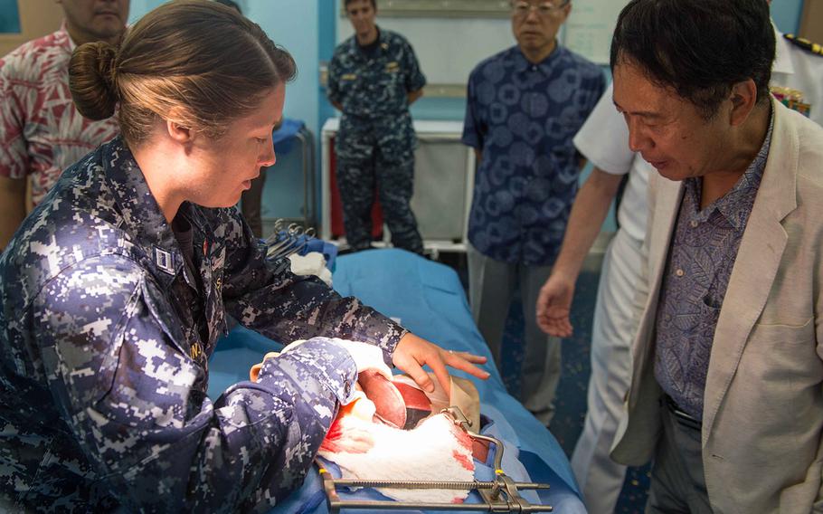 Lt. Jessica Naranjo, left, assigned to the Military Sealift Command hospital ship USNS Mercy, displays a surgical mannequin to Toyoei Shigeeda, consul general of Japan in Honolulu, while in the operating room aboard Mercy, July 9, 2014. Mercy is in Pearl Harbor taking part in RIMPAC.  