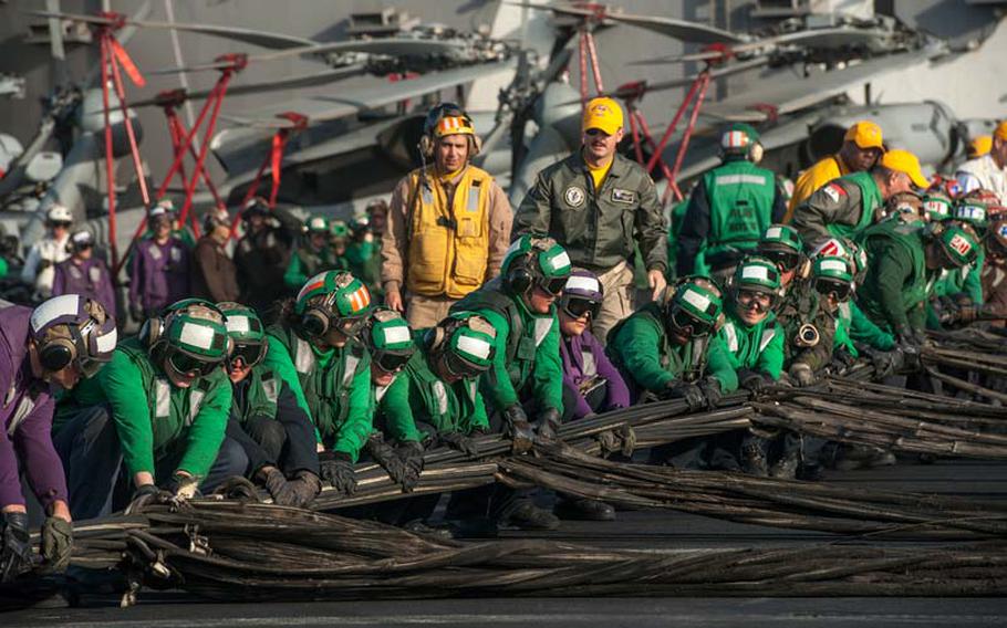 Sailors rig the emergency-landing barricade during a flight deck drill aboard the aircraft carrier USS Vinson in June 2014.
