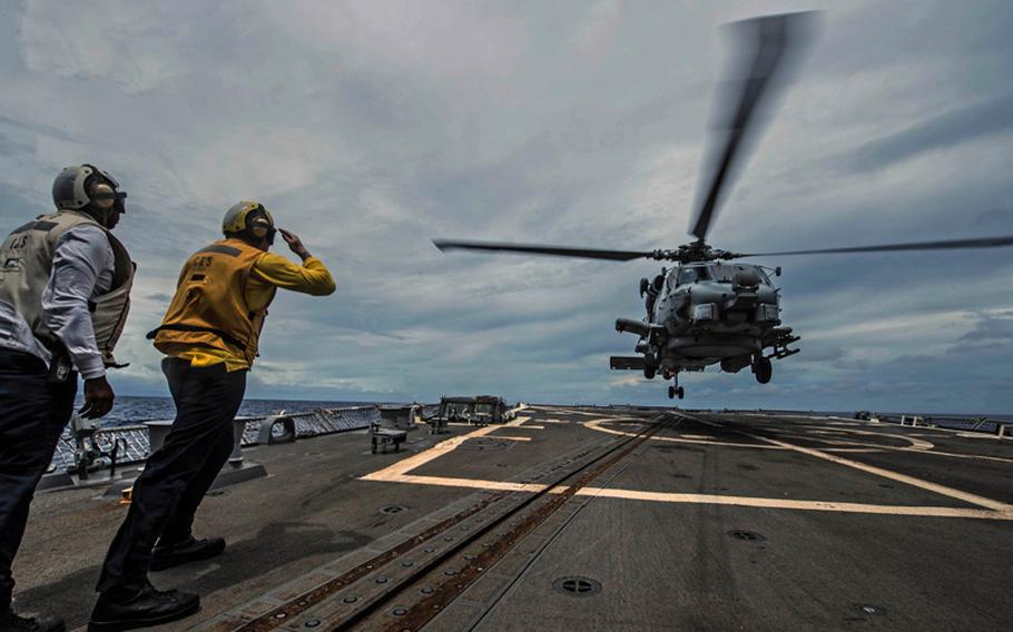 Boatswain's Mate 3rd Class Tyler Joosten from Salt Lake City, Utah, signals an MH-60R Sea Hawk helicopter from the Saberhawks of Helicopter Maritime Strike Squadron 77 as it launches off the flight deck of the Arleigh Burke-class destroyer USS Halsey. 