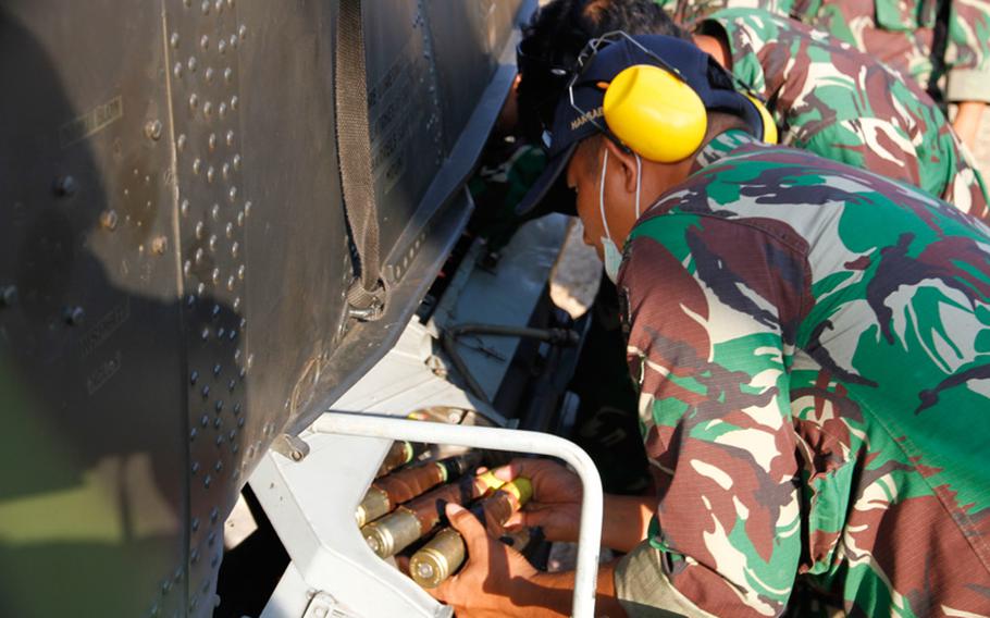 Members of the flight crew for an Indonesian attack helicopter remove unfired live ammo after a training flight during Garuda Shield in Indonesia.