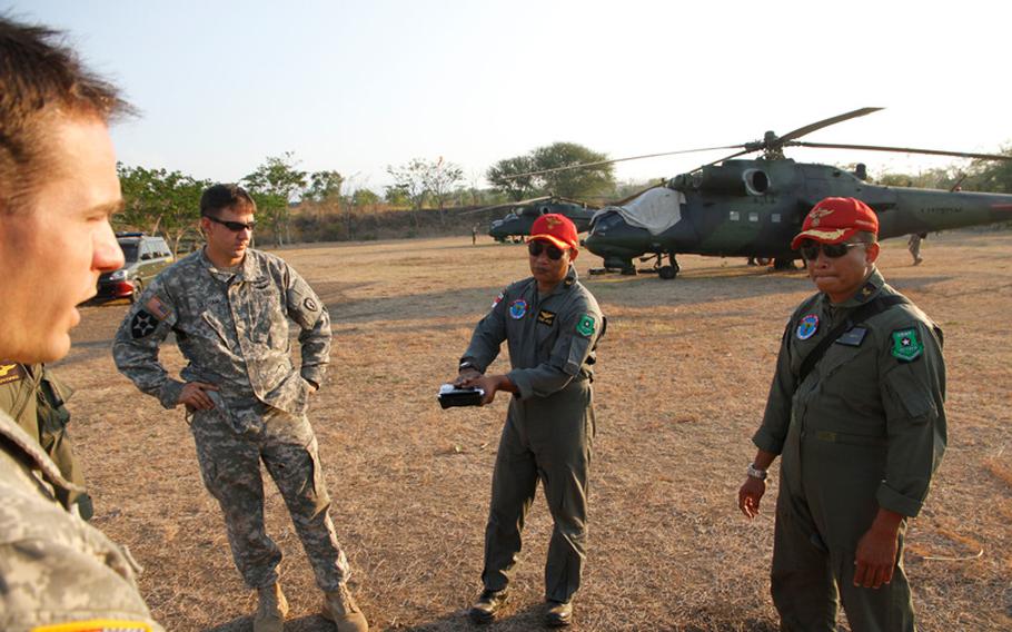 American and Indonesian army aviators discuss a practice flight after landing during the Garuda Shield exercise in Indonesia. The Americains flew Apaches, while the Indonesians piloted Russian-made MI-35 assault helicopters, seen in the background.