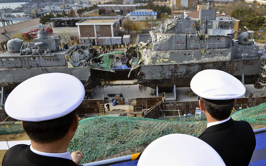 U.S. and South Korean officials look at the remains of the Republic of Korea ship Cheonan while touring a port facility in Pyeongtaek on Nov. 22, 2013. The Pohang-class corvette was sunk by a North Korean torpedo March 26, 2010.