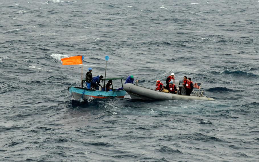 An orange flag, signaling distress, waves from a boat carrying stranded Philippine fishermen on Wednesday, March 25, 2015. Sailors attached to the U.S. 7th Fleet flagship USS Blue Ridge rescued the five fishermen, whose boat had suffered a mechanical breakdown.