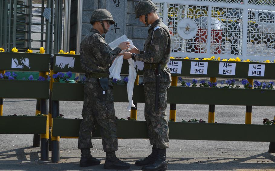 South Korean troops outside the gate of the Ministry of National Defense in Seoul remove protest signs in Korean and English on April 10, 2015. The signs opposed the possible deployment of the THAAD missile defense system to South Korea.



