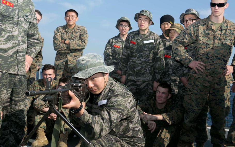 Republic of Korea Marine demonstrates shooting positions for the K3 light machine gun to U.S. Marines from Company G, Battalion Landing Team, 2nd Battalion, 4th Marines, 31st Marine Expeditionary  Unit, on the flight deck of the Seong-In-Bong, at sea, March 28, 2015.