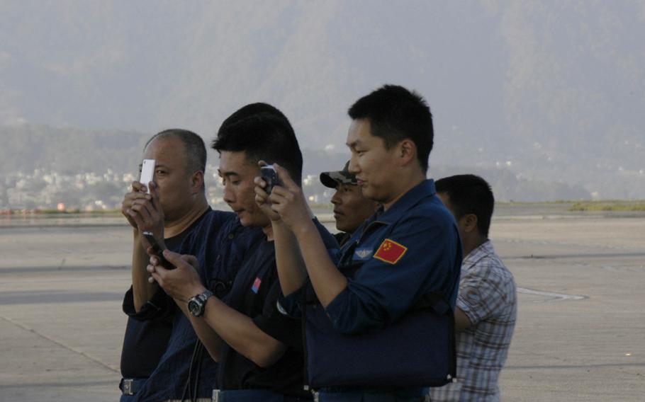 Chinese personnel take photographs of U.S. Marines unloading a helicopter in Kathmandu, Nepal Sunday, May 3, 2014. 