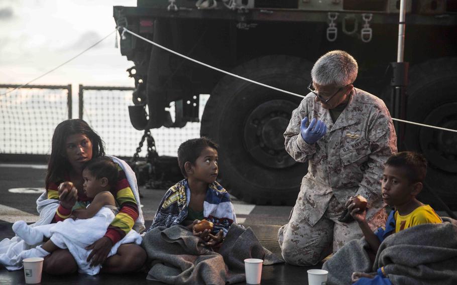 Navy Lt. Diane Hampton, the chaplain for Combat Logistics Battalion 15, 15th Marine Expeditionary Unit, comforts a woman and children aboard the amphibious dock landing ship USS Rushmore on June 10, 2015. The Rushmore rescued 65 people from a bamboo raft adrift in the Makassar Strait, off Indonesia. 

