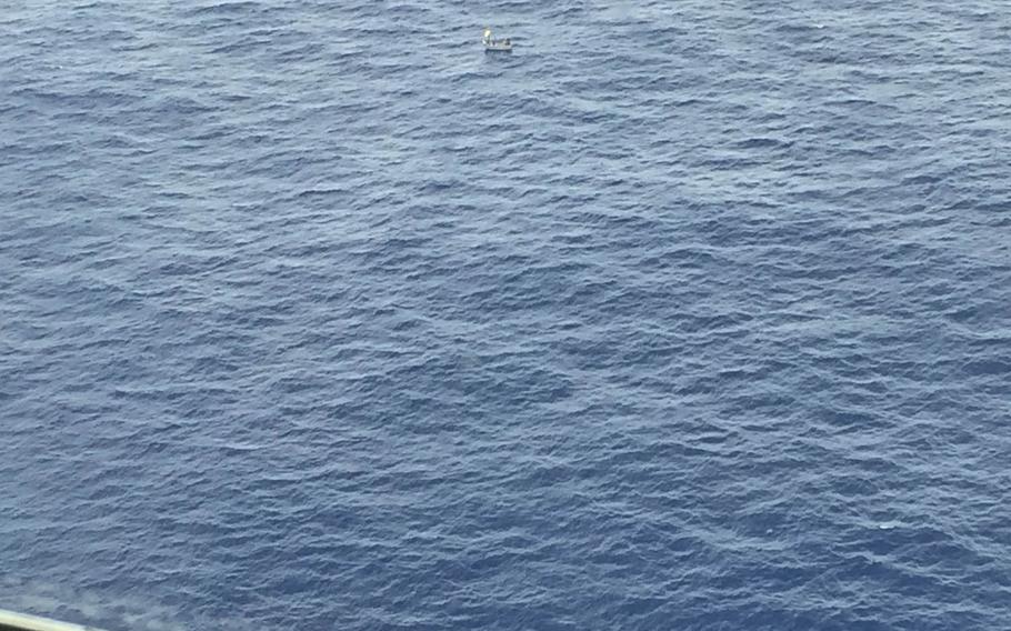 Five men in a 14-foot aluminum skiff signal to the crew of an HC-130 Hercules from Coast Guard Air Station Barbers Point out of Oahu, Hawaii, before being rescued Saturday, July 11, 2015,  184 miles east-northeast of Teraina Island, Kiribati. 