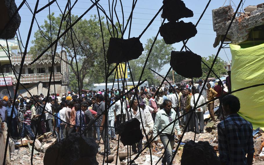 Onlookers and people looking for their missing relatives gather at the site of Saturday's explosion in the town of Petlawad in central Madhya Pradesh state, India, Sunday, Sept. 13, 2015. Police in central India on Sunday were looking for a man who was being blamed for a massive explosion at a restaurant that killed dozens, as angry residents protested the way the authorities were handling the case. (AP Photo/Ritesh Trivedi)