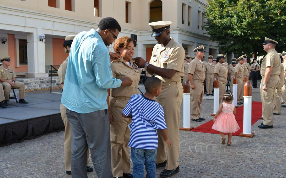 Chief Petty Officer Desiree Wade has her anchors pinned on with the help of husband Reginal, foreground, with children Reginal Jr. and Zoee on hand at a pinning ceremony Wednesday, Sept. 16, 2015, in Naples Italy.
 
