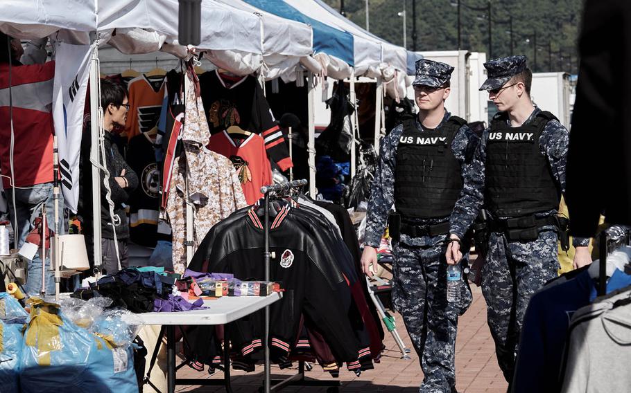 Sailors from the USS Ronald Reagan patrol a street market on the pier in Busan, South Korea, Friday, Oct. 30, 2015.