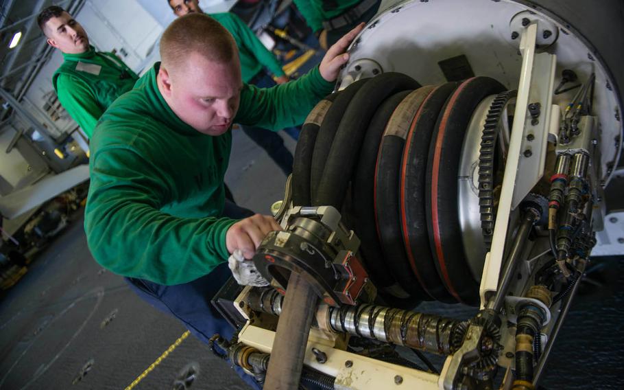 Aviation structural mechanic 2nd Class Stephen McGinness cleans an aerial refueling store pod in the hangar bay of the USS John C. Stennis, Nov. 4, 2015. The Stennis is the flagship of the Navy's "Great Green Fleet" initiative that will use a biofuel-petroleum mix for an entire carrier strike group.