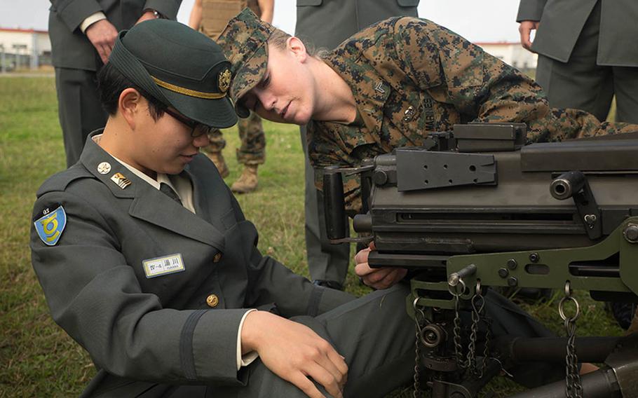 Cpl. Malynn Ochsner shows Japan Ground Self-Defense Force officer candidate Ayako Yukawa how to operate a MK19 machine gun, MOD 3 on Camp Kinser, Okinawa, Japan, Friday, Jan. 15, 2016. Three hundred and sixty JGSDF officer candidates watched Marine Corps Martial Art Program demonstrations, learned the capabilities of various machine guns the Marine Corps uses, and observed a static display of motor transportation vehicles. Ochsner, from Pflugerville, Texas, is a distribution management specialist with 3rd Supply Battalion, CLR-35, 3rd Marine Logistics Group, III Marine Expeditionary Force.