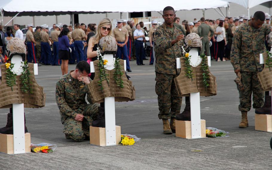 Mourners pause at crosses representing the 12 Marines who died in helicopter crashes Jan. 14 in Hawai. The crosses were adorned with flight gear, boots and Hawiian leis during a memorial Jan. 22, 2016,  at Marine Corps Base Hawaii.