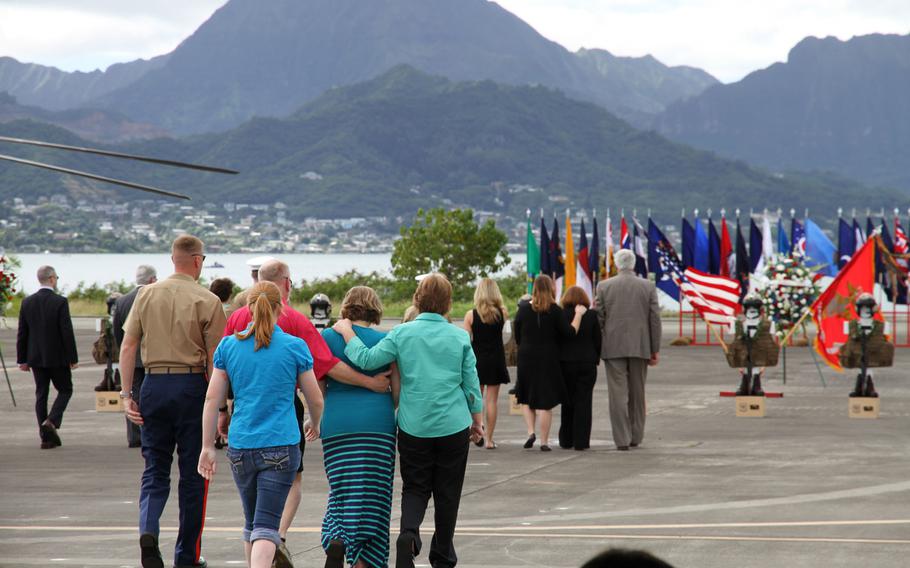 Family members of the 12 Marine aviators lost at sea in helicopter crashes on Jan. 14  walk to white crosses representing their loved ones during a memorial Friday at Marine Corps Base Hawaii. No remains of the Marines have yet been found.